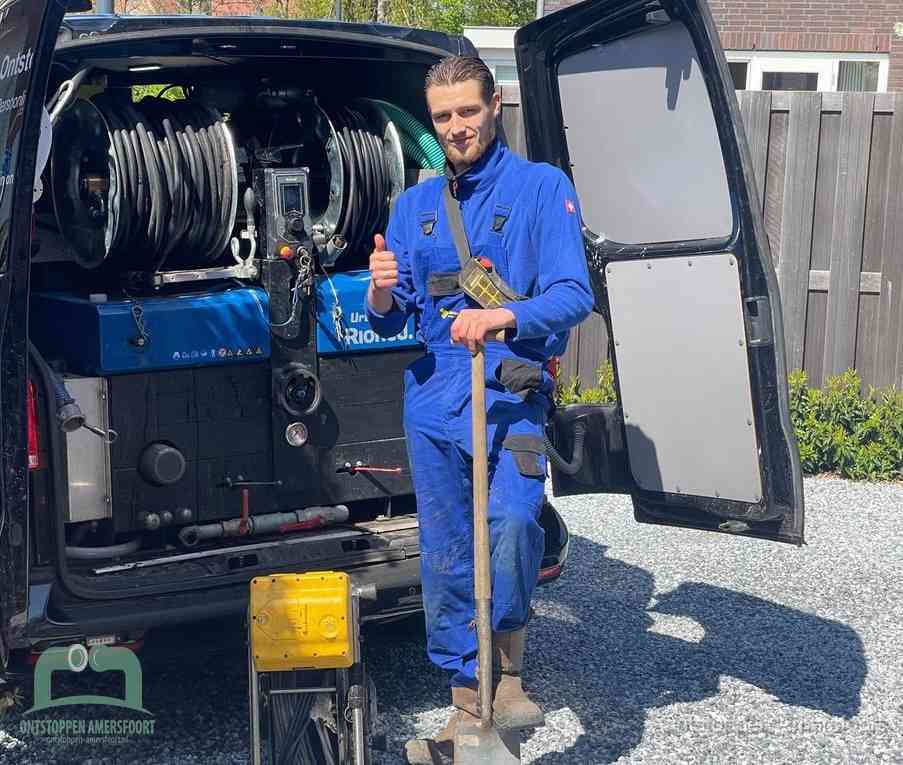 Een tevreden monteur met opgestoken duim naast de bestelbus, slim ingrijpen bespaart kosten bij een verstopte afvoer in Amersfoort