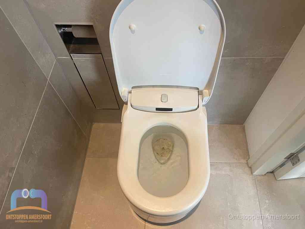 Een wit hangtoilet waarin een prop wc-papier op het water blijft drijven, een duidelijk signaal van een verstopte wc in Amersfoort