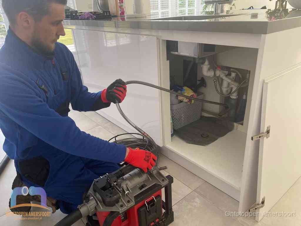 Een monteur reinigt de keukenafvoer grondig met een veermachine om terugkerende gootsteenverstoppingen te voorkomen in Amersfoort