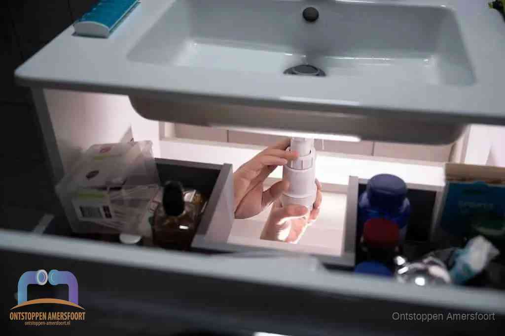 Een pompfles met zeep boven een wastafel in de toiletruimte, de warm water en afwasmiddel-methode om de wc te ontstoppen in Amersfoort