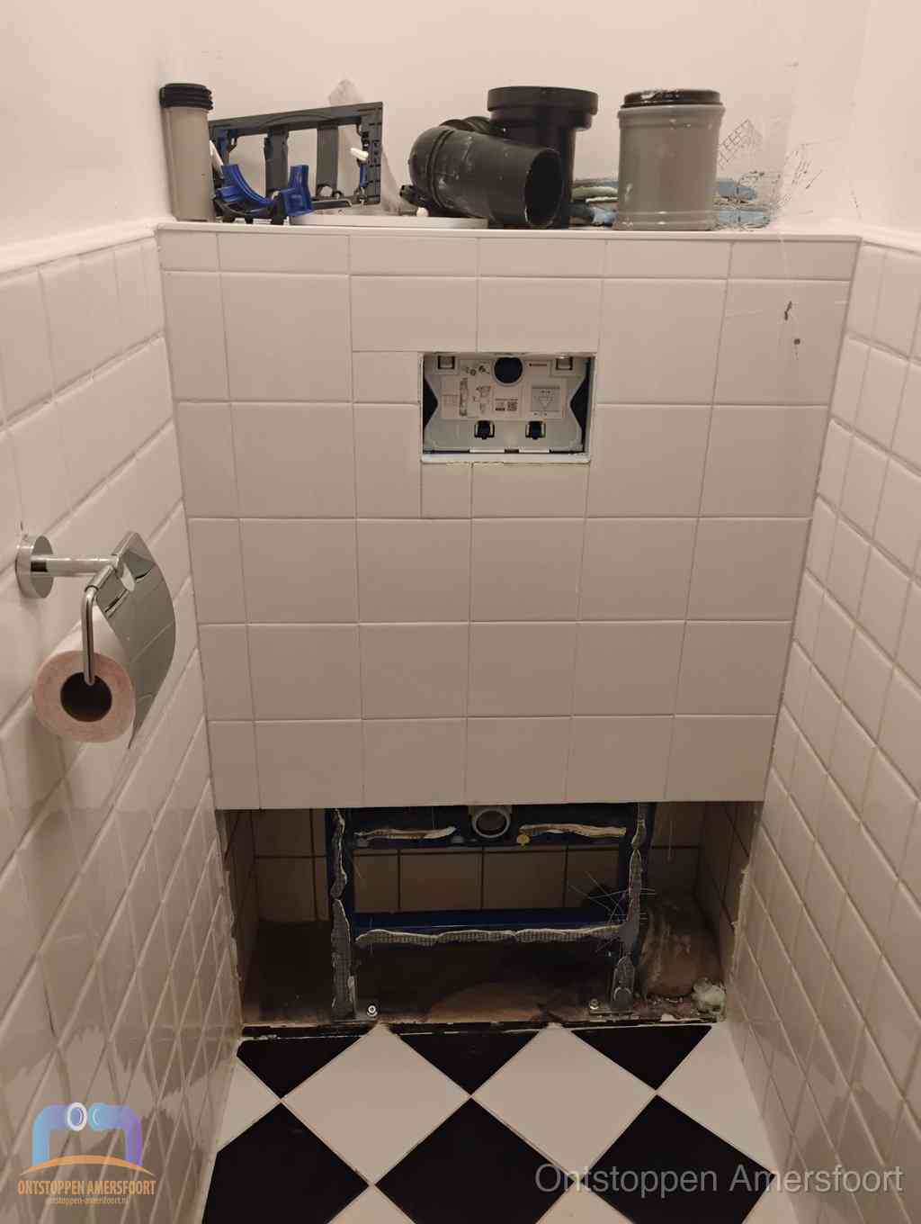Een toiletruimte waar het hangtoilet en de inbouwreservoir-onderdelen zijn vrijgelegd voor onderhoud, periodiek nazicht voorkomt een wc-verstopping in Amersfoort